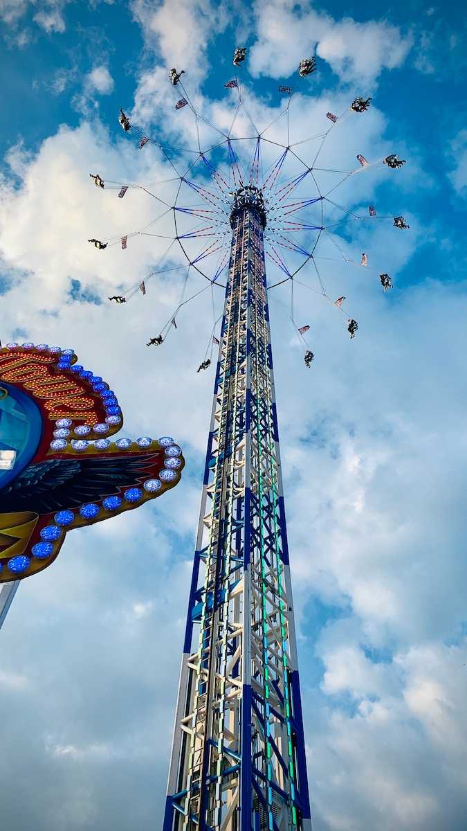 a ferris wheel and a carnival ride against a cloudy blue sky